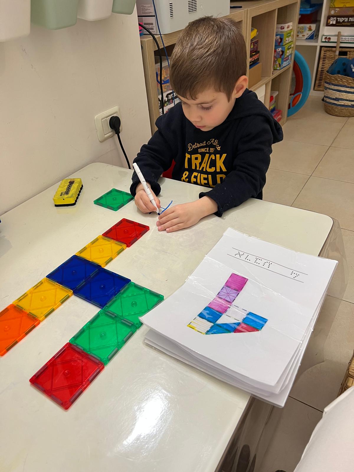 ילד יוצר אותיות במגנטים